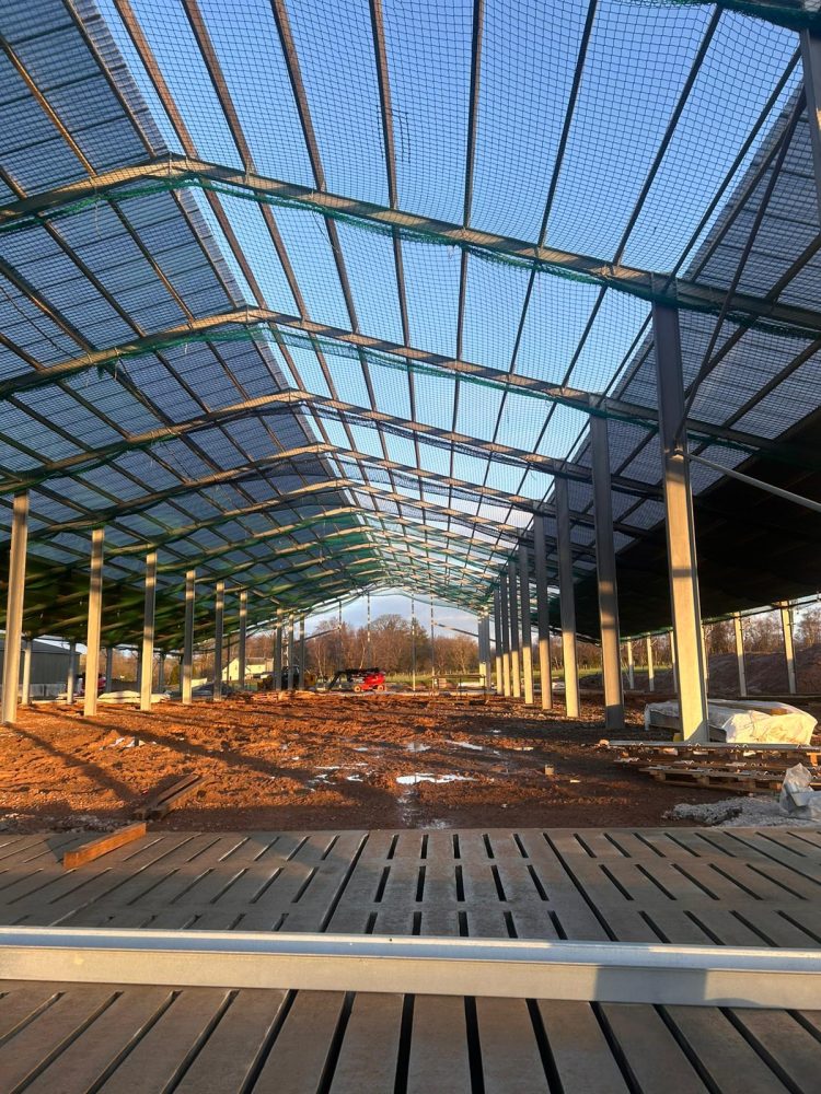 Inside our custom steel building, with edge protection and safety nets in place as the roof build stage progresses